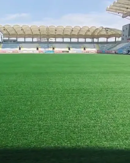 A finished stadium pitch seen from pitch level, the stand behind it